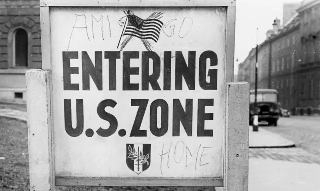 Eine mit "Ami go home" beschmierte Zonengrenzentafel "Entering U.S. Zone".