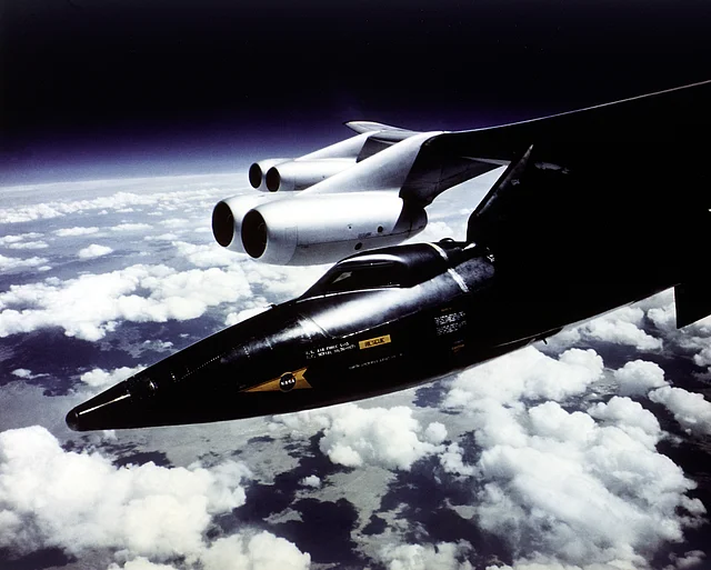 Ein X-15 Raketenflugzeug vor dem Start unter den Flügeln eines B-52 Bombers eingehängt.