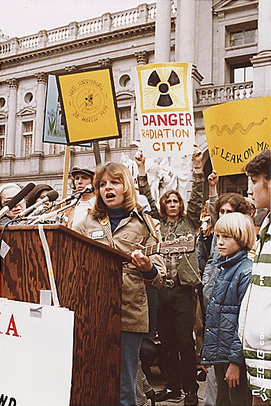 Frauen und Kinder mit Transparenten (Danger. Radiation City) und eine Frau am Rednerpult