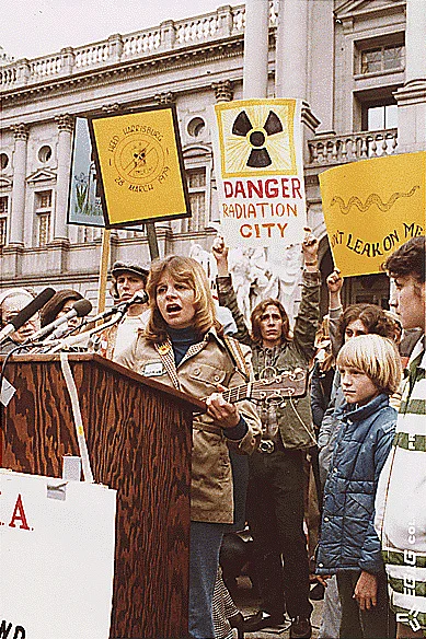 Frauen und Kinder mit Transparenten (Danger. Radiation City) und eine Frau am Rednerpult