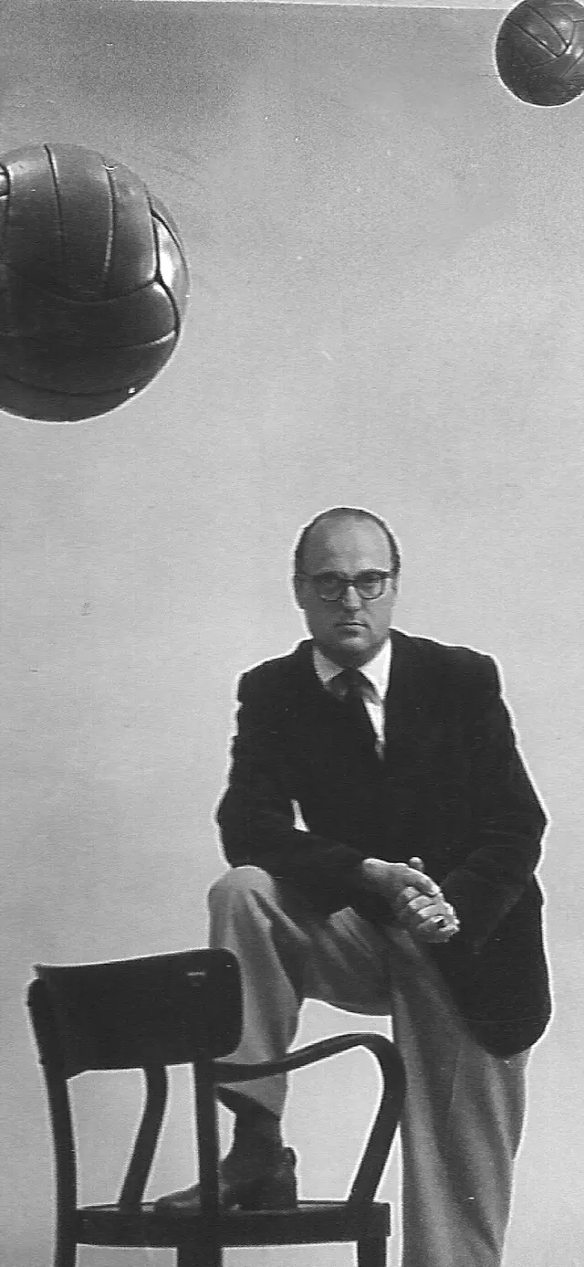 Portrait des  Sportreporters stehen, mit einem Fuß auf einem Sessel und hängenden Fußbällen