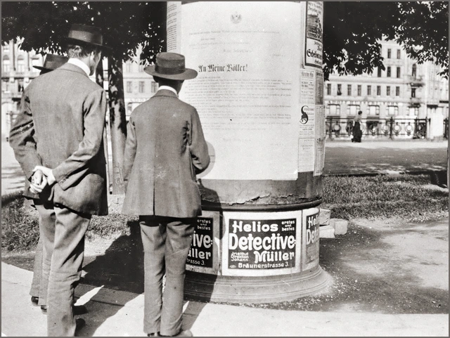Passanten lesen die Kriegserklärung an einer Litfaßsäule