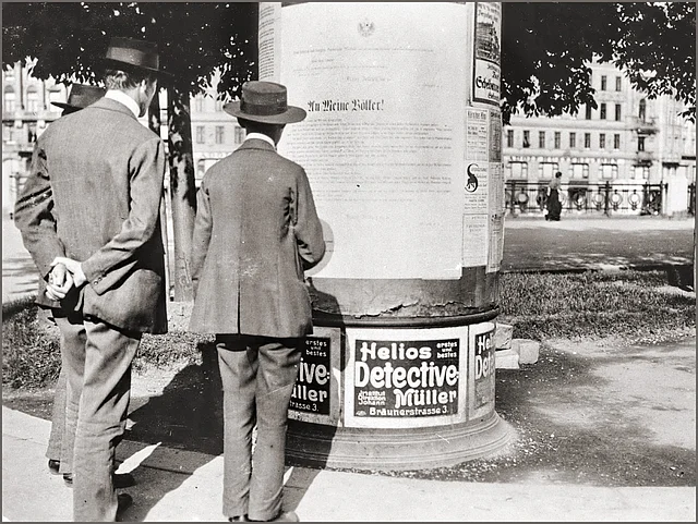 Passanten lesen die Kriegserklärung an einer Litfaßsäule