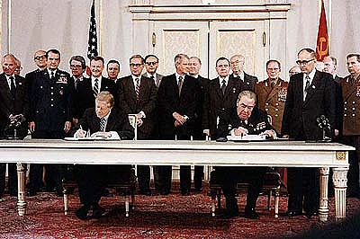 US-Präsident Jimmy Carter und der Parteichef der KPdSU, Leonid Breschnjew, unterzeichnen den Vertrag. Im Hintergrund viele Männer...