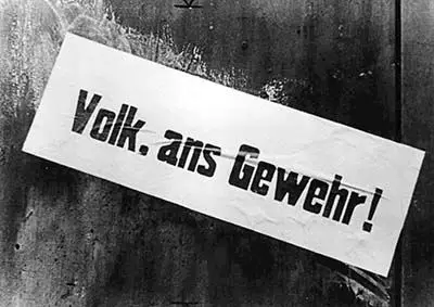 Der Volkssturm ist Thema. Junge und Alte werden noch in den Kampf geschickt. Klebestreifen an einer Hausmauer, 1945 Auf dem Streifen: "Volk, ans Gewehr"
