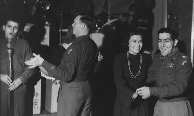Zwei tanzende Paare mit US-Soldaten, ein singender Soldat am Mirofon und im Hintergrund die US-Tanzband.