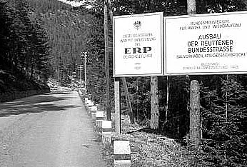 Zwei große Schilder am Straßenrand, der auf beiden seiten bewaldet ist, auf denen die Projektfinanzierung aus dem ERP erklärt wird. (Text am Foto aber kaum lesbar)