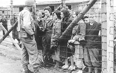 Frauen und Kinder sprechen mit einem US-Soldaten. Unterhaltung durch den Stacheldrahtzaun des Konzentrationslagers