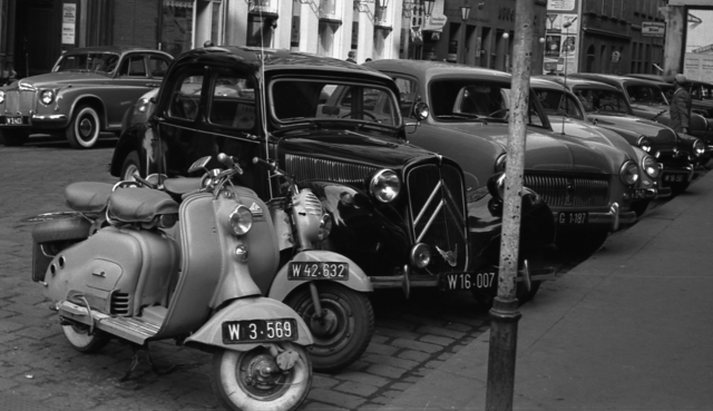 Straßenbild mit parkenden Motorrollern und PKW.