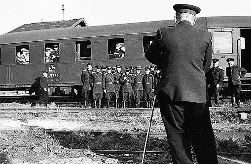 Letzte Abschiedsfoto. Soldaten posieren vor einem Waggon. Im Vordergrund die Rückenansicht des fotografierenden Soldaten.