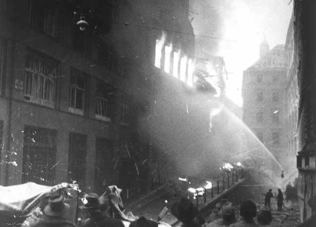 Bombenschaden: Löscheinsatz bei einem brennenden Haus in der Salvatorgasse, Publikum im Vordergrund
