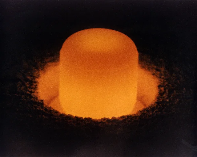 Ein Plutoniumdioxid-Pellet: Ein rotglühender Zylinder in schwarzer Umgebung.