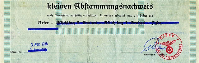 Farbfoto eines Kleinen Abstammungsnachweises, der auch als "Ariernachweis" bezeichnet wird. Auf dem Auschnitt der Urkunde mit grünem Untergrund steht: "kleinen Ariernachweis. nach überpfüften umseitig erscichtlichen Urkunden erbracht und gilt daher als Arier" die weiteren Optionen "Mischling 2. Grades", "Mischling 1. Grades" und "Jude" sind mit einem blauen Stift durchgestrichen. Ausgestellt wurde das Dokument in Wien und trägt den Datumsstempel 3. August 1938. Das Dokument ist unterschrieben und trägt einen roten, runden Stempel mit Reichsadler und Hakenkreuz.