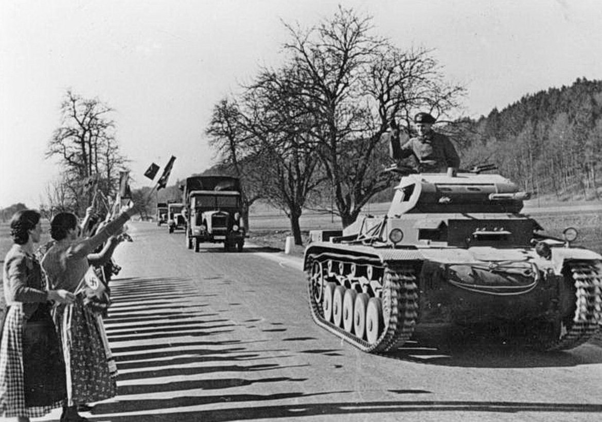 Motorisierte deutsche Truppen überqueren am 13. März 1938 die Grenze an der Zollstation Schärding. Ein Panzerspähwagen fährt durch ein Tor.