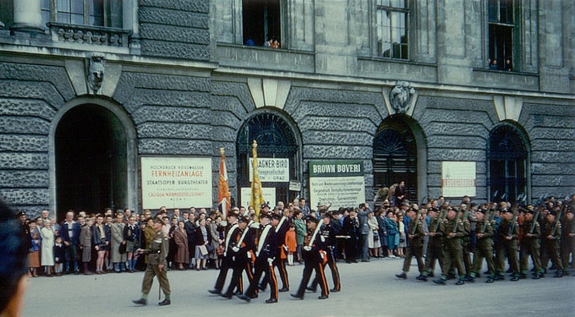 Farbfoto einer Militärparade mit Gebäude und Fenstern der Hofburg im Hintergrund