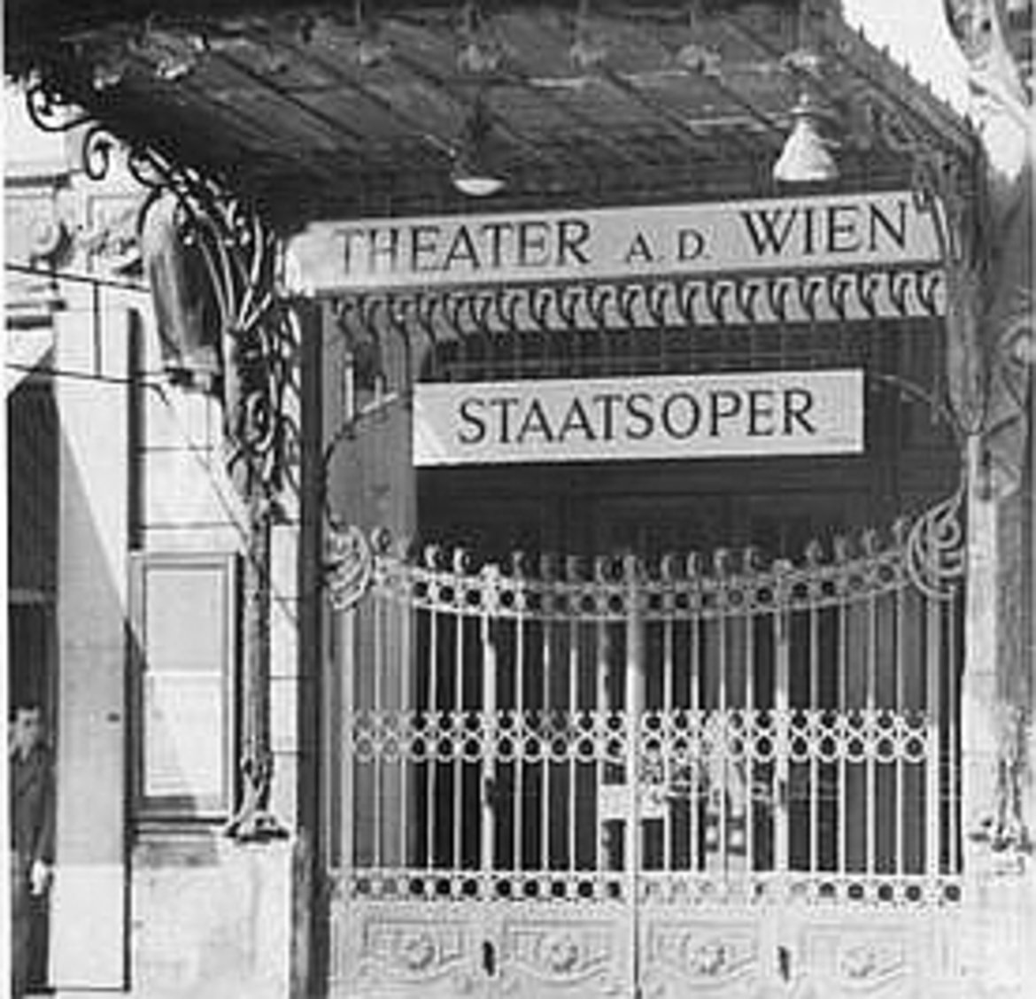 Das Eingangsgittertor des Theaters mit zwei Schildern: "Theater a. d. Wien" und "Staatsoper"