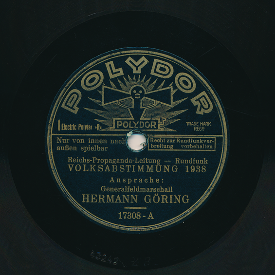 Das Polydor-Label einer Schellackplatte mit einer Ansprache von Generalfeldmarschall Hermann Göring zur Volksabstimmung 1938 von der Reichs-Propaganda-Leitung Rundfunk.
Außerdem ist zu lesen: "Recht zur Rundfunkverbreitung vorbehalten" und " Nur von innen nach außen spielbar".
Die Matrizennummer lautet: 17308-A