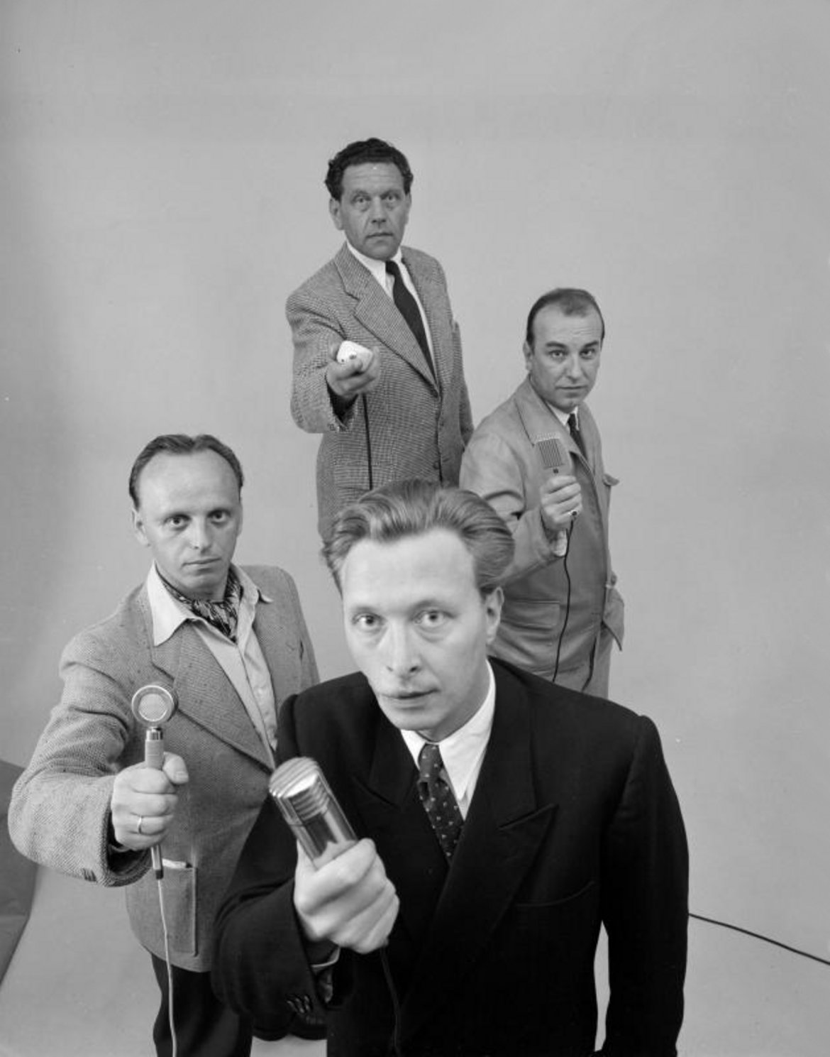 Peter Doerre, Ernst Hellebrand, Viktor Fit und Gerhard Stappen mit je einem Mikrofon in der Hand in die Kamera blickend